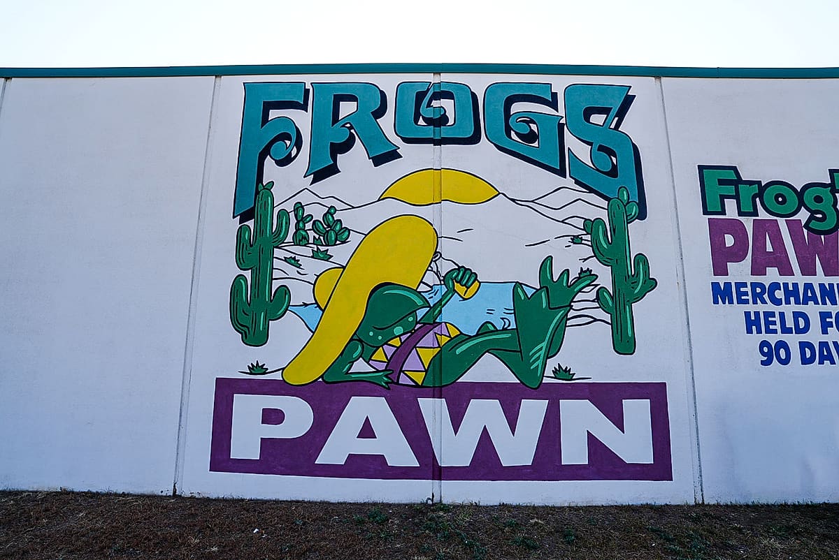 The Frog's Pawn frog mural painted on the side of the building